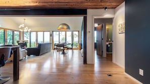 A spacious living area with a wooden floor, a dining table, and a sofa. - Modern Catskills Escape w/ Open Living, Steam Shower, & Hot Tub w/ Mountain Views, Minutes From Woodstock & Trails Suncliff Vista (Glenford)