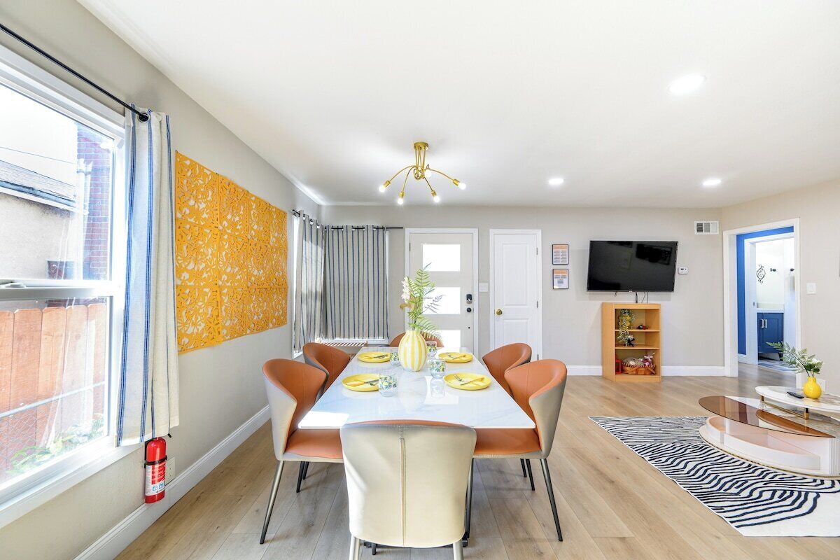 Un coin repas avec une table dressée pour quatre personnes, entourée de chaises, d’un téléviseur et d’une bibliothèque.