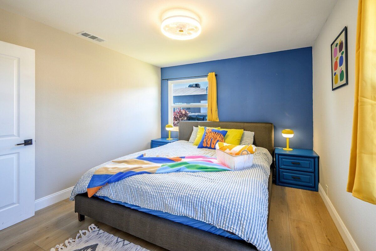 Una camera da letto con un letto, comodini, una finestra con tende e un quadro appeso al muro.