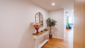 A hallway with a white console table, a mirror, and a potted plant. - Sea-View 3BR, Rooftop Pool, Secure Parking & Study (Wynnum)
