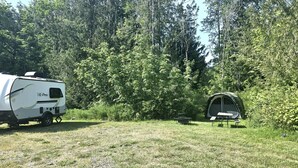 A camping site with a trailer and a tent.