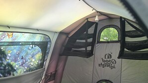 A tent with a mattress inside, a window, and a hanging light fixture.