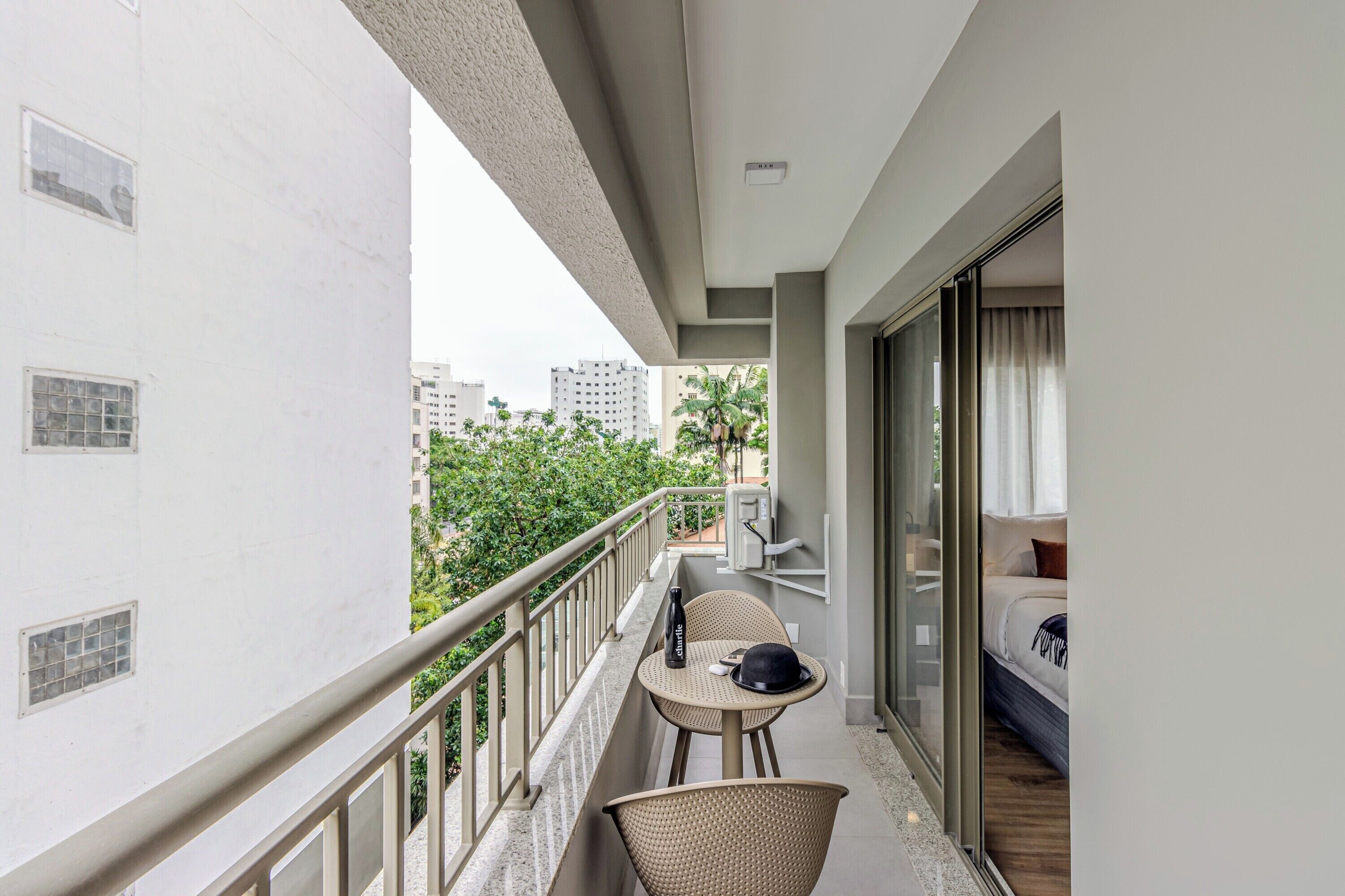 A balcony with a table, chairs, and a bed with a curtain.