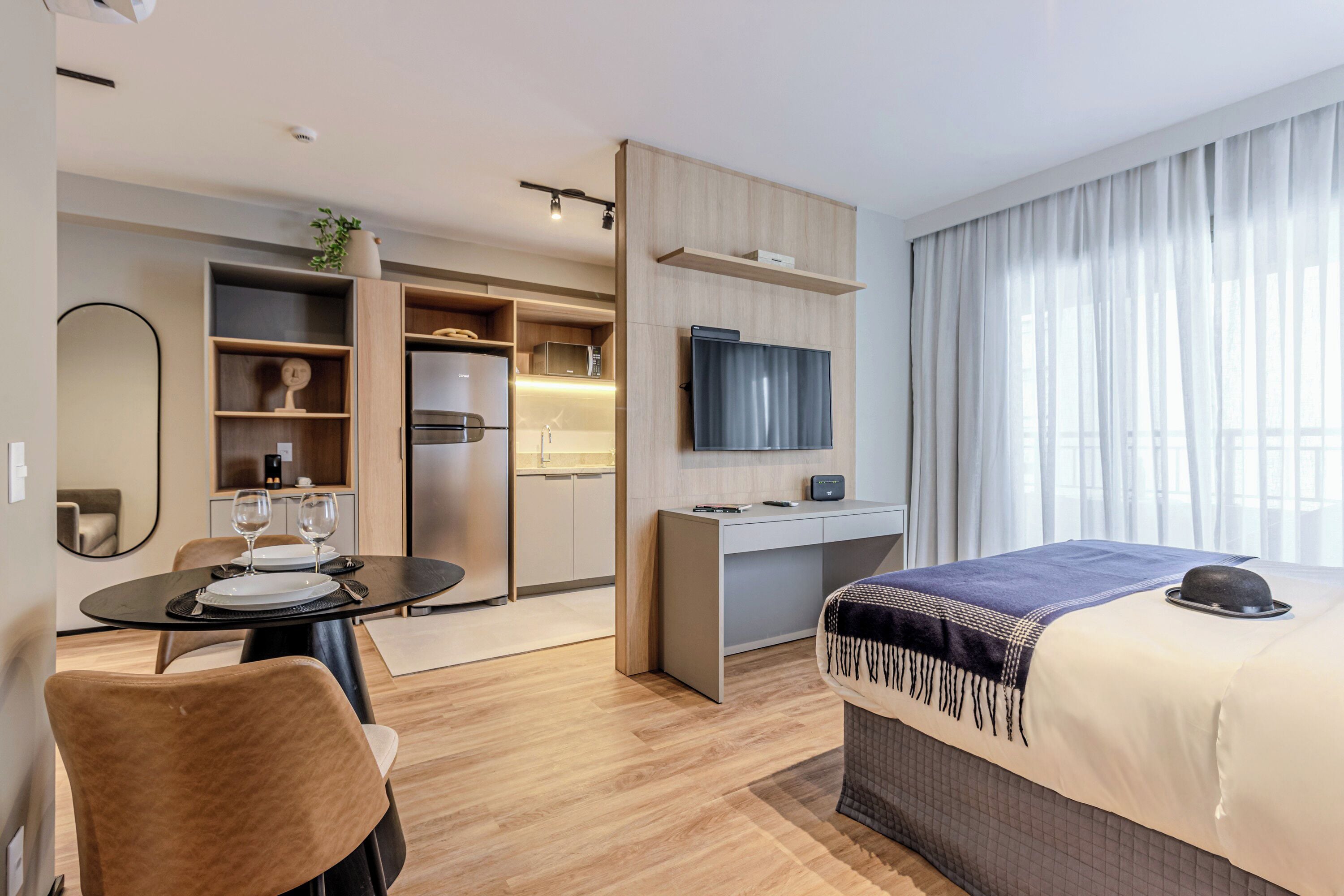 Ein modernes Hotelzimmer mit Bett, Schreibtisch, Esstisch und einer Küchenzeile.