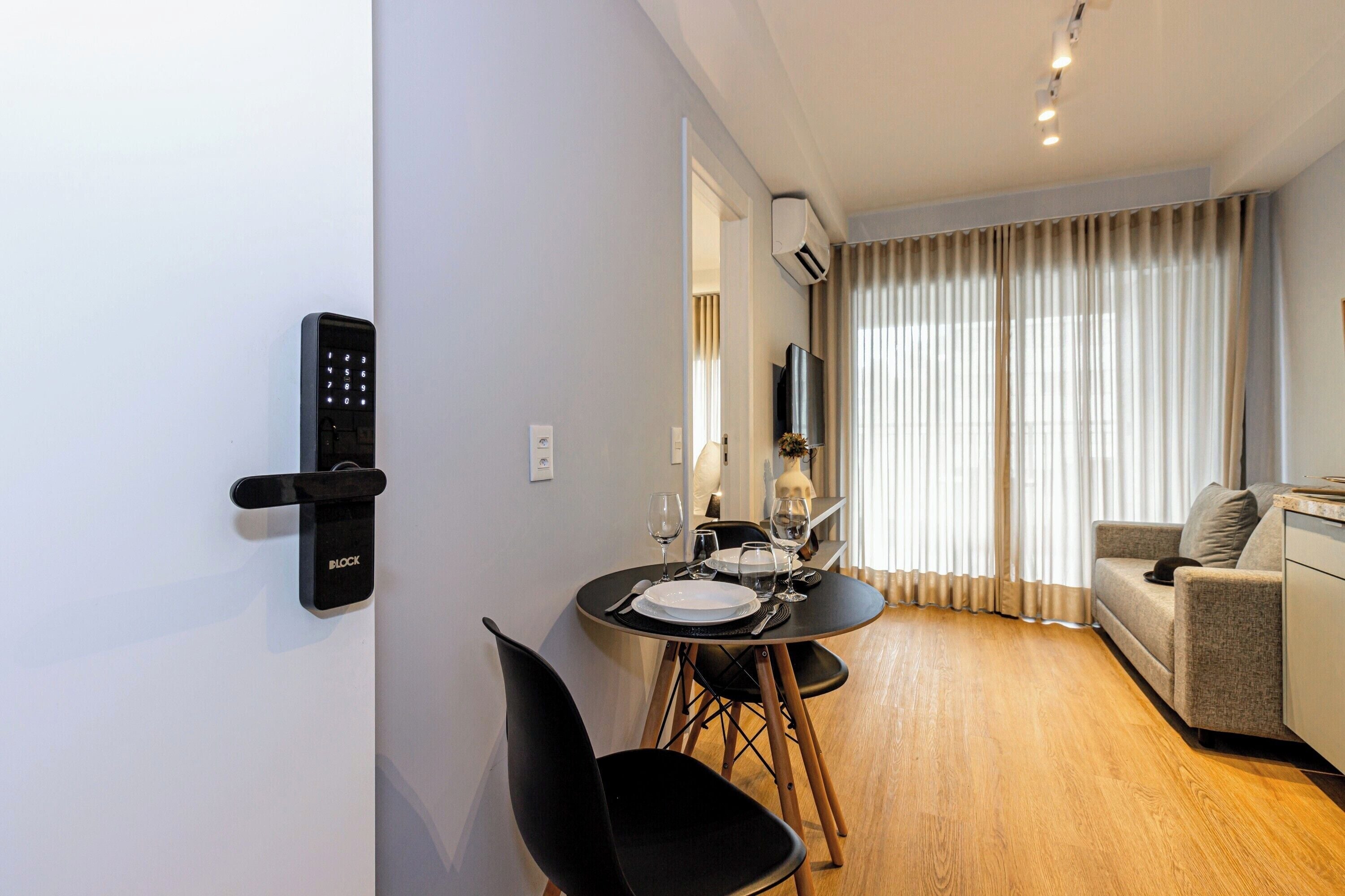 A modern living room with a sofa, a dining table with chairs, and a TV mounted on the wall.