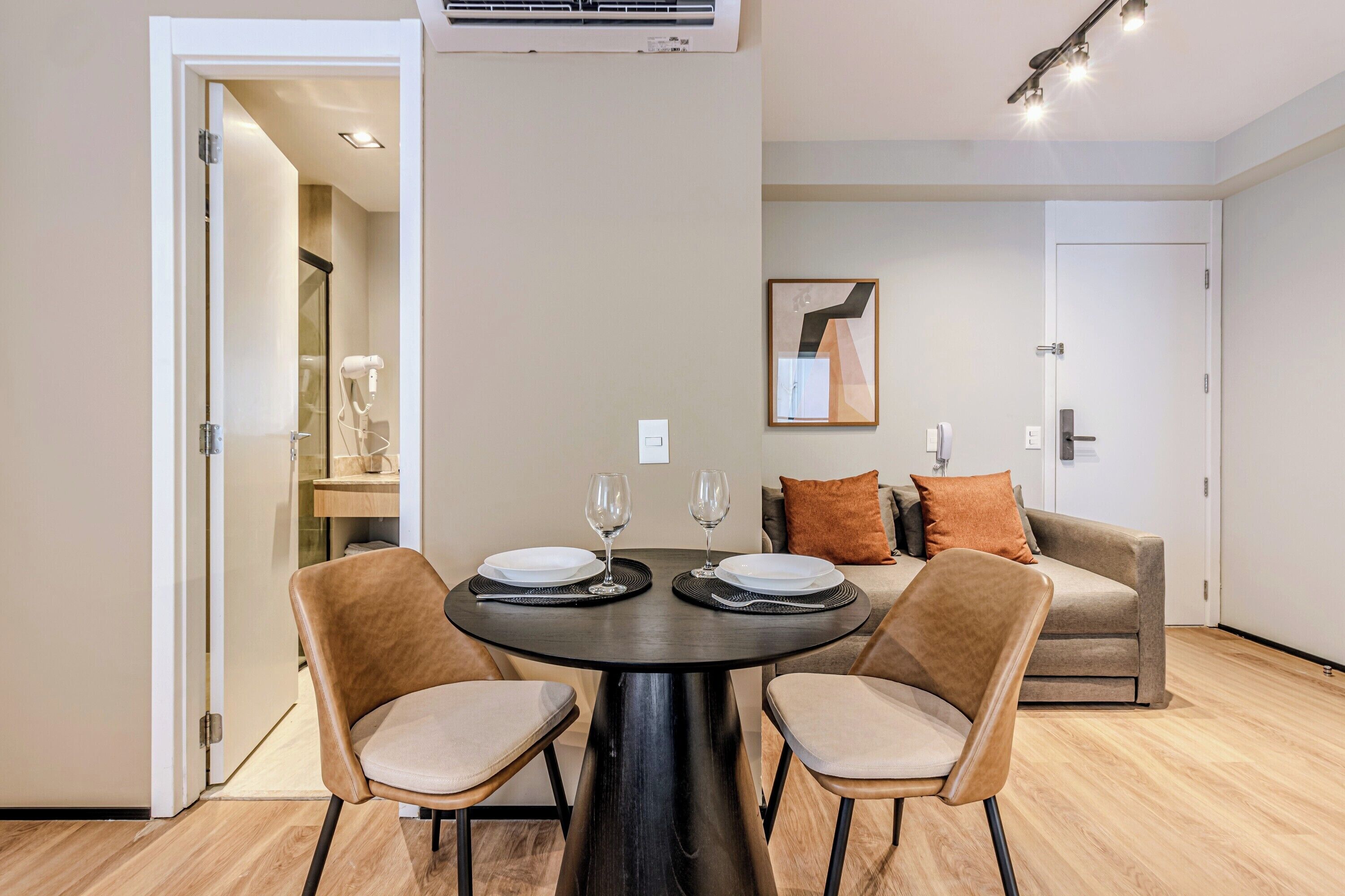 Un área de comedor moderna con una mesa redonda, dos sillas y un sofá al fondo.