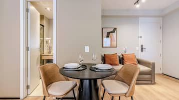 Un área de comedor moderna con una mesa redonda, dos sillas y un sofá al fondo.