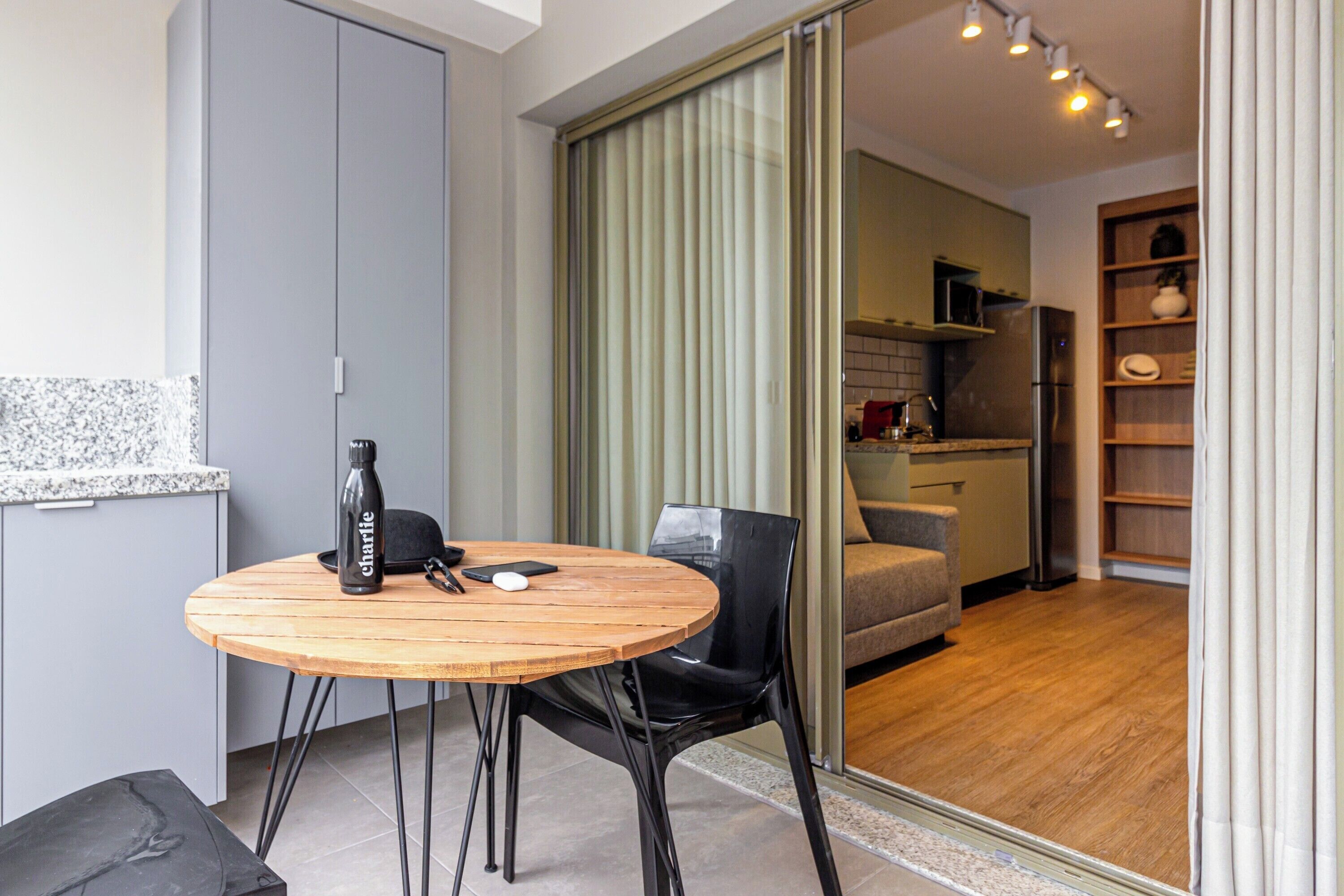 A modern kitchen with a microwave, refrigerator, and wooden shelves.