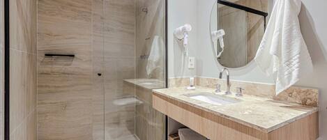 Een moderne badkamer met een douchecabine van glas, een houten wastafelmeubel met een wastafel en een grote spiegel.