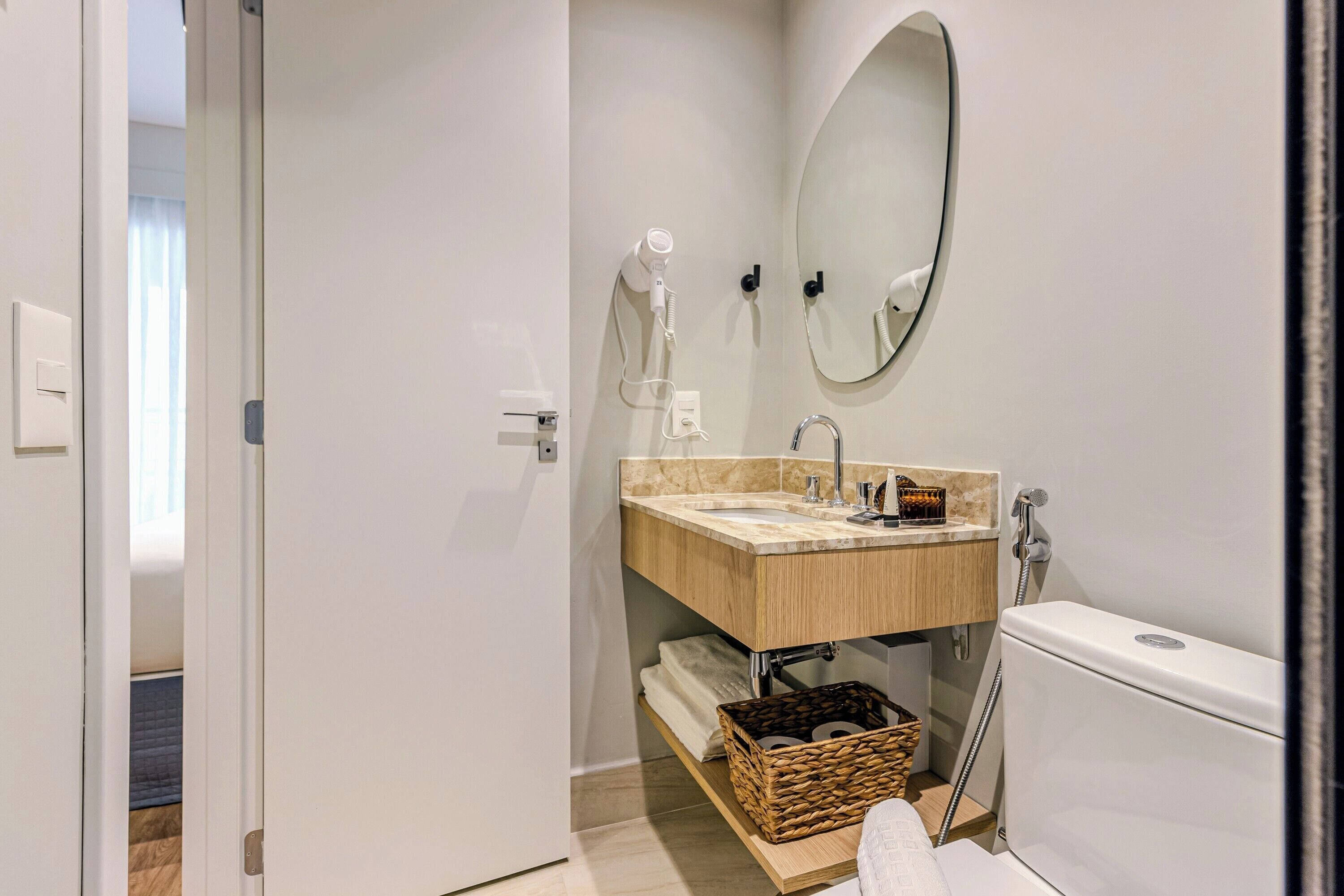 A modern bathroom with a wooden vanity, a large mirror, and a toilet.