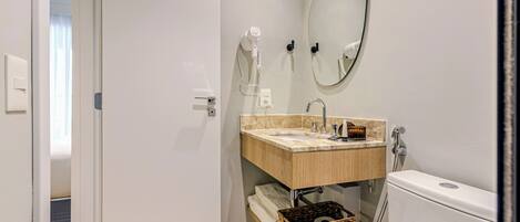 A modern bathroom with a wooden vanity, a large mirror, and a toilet.