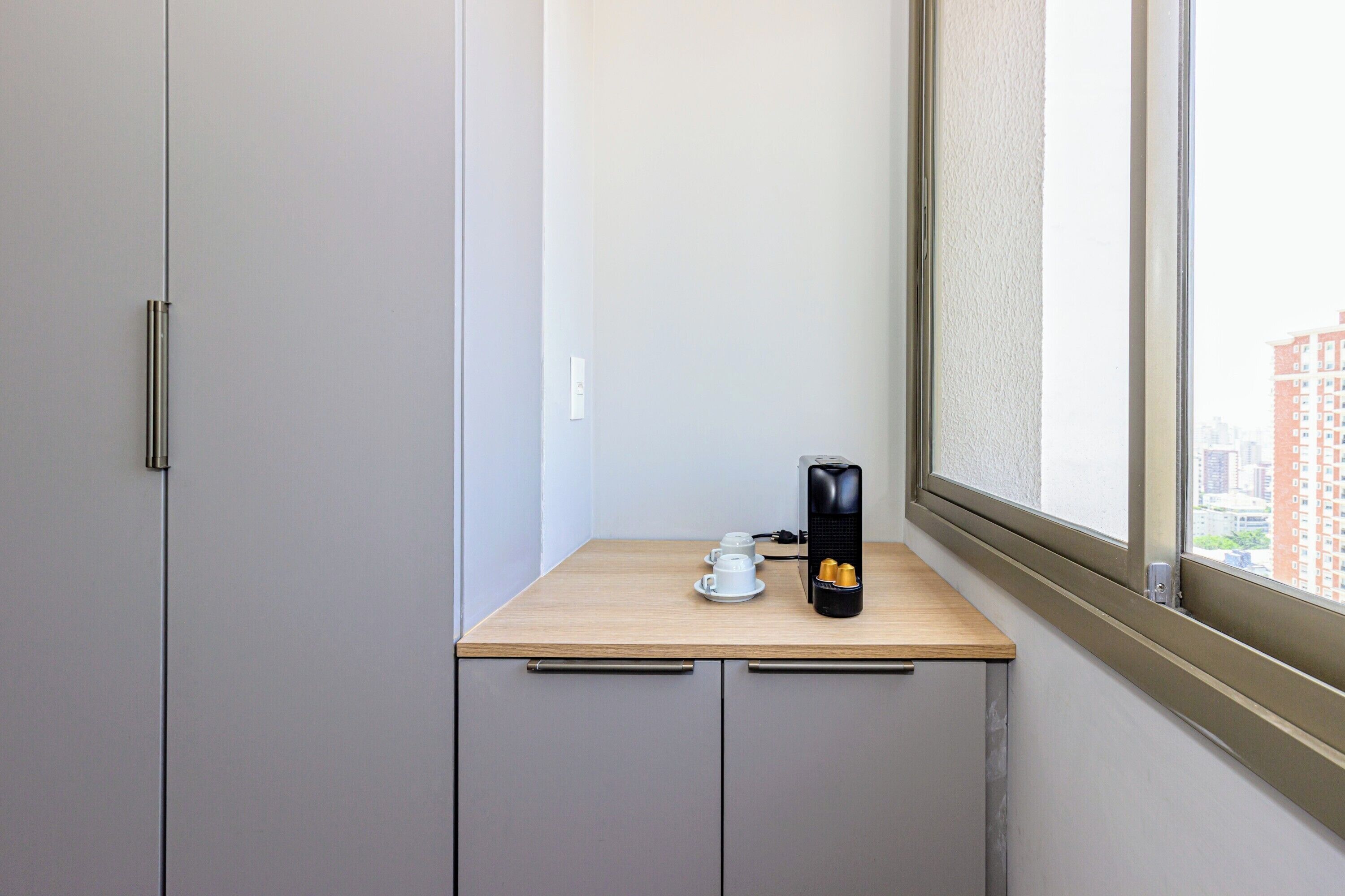 Una pequeña kitchenette con cafetera, una taza y un plato sobre una encimera de madera.