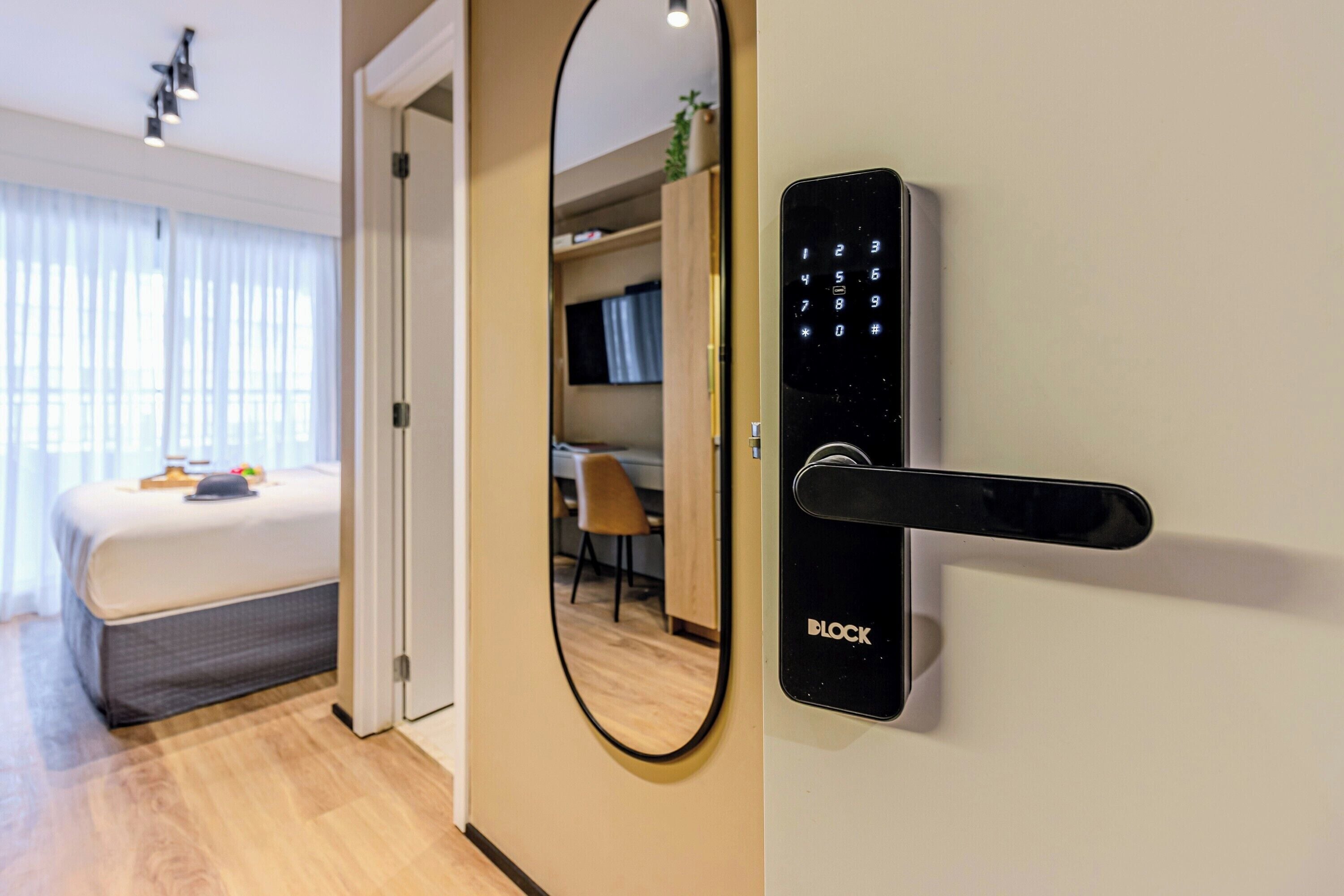 A modern hotel room with a bed, a desk, and a wardrobe.