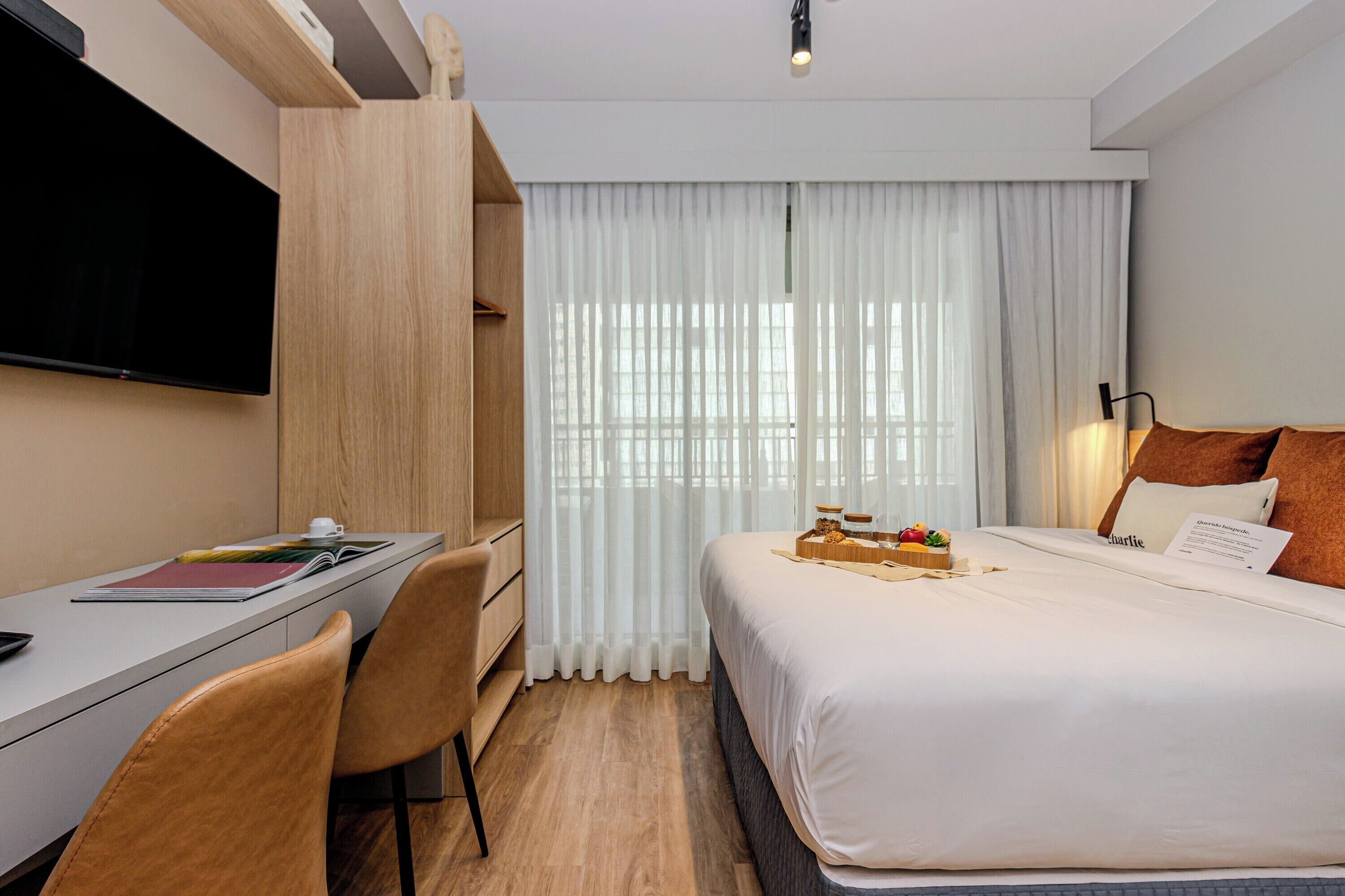 A hotel room with a bed, a desk, a chair, and a TV.