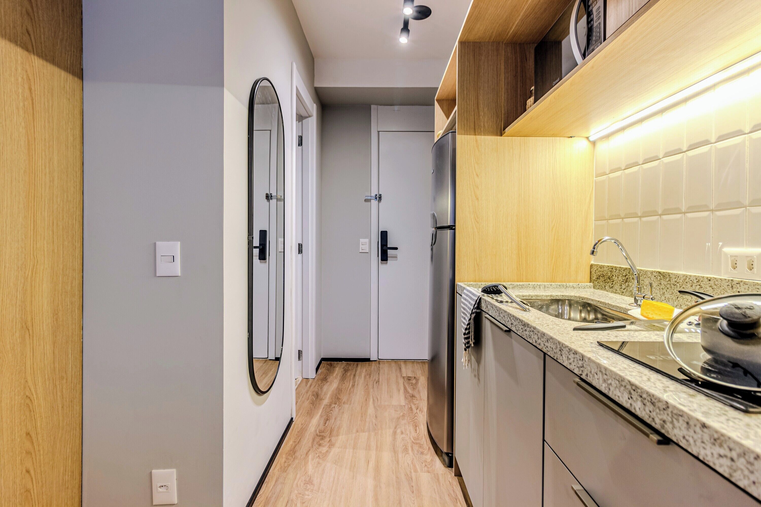 A modern kitchen with a granite countertop, stainless steel appliances, and a wooden floor.