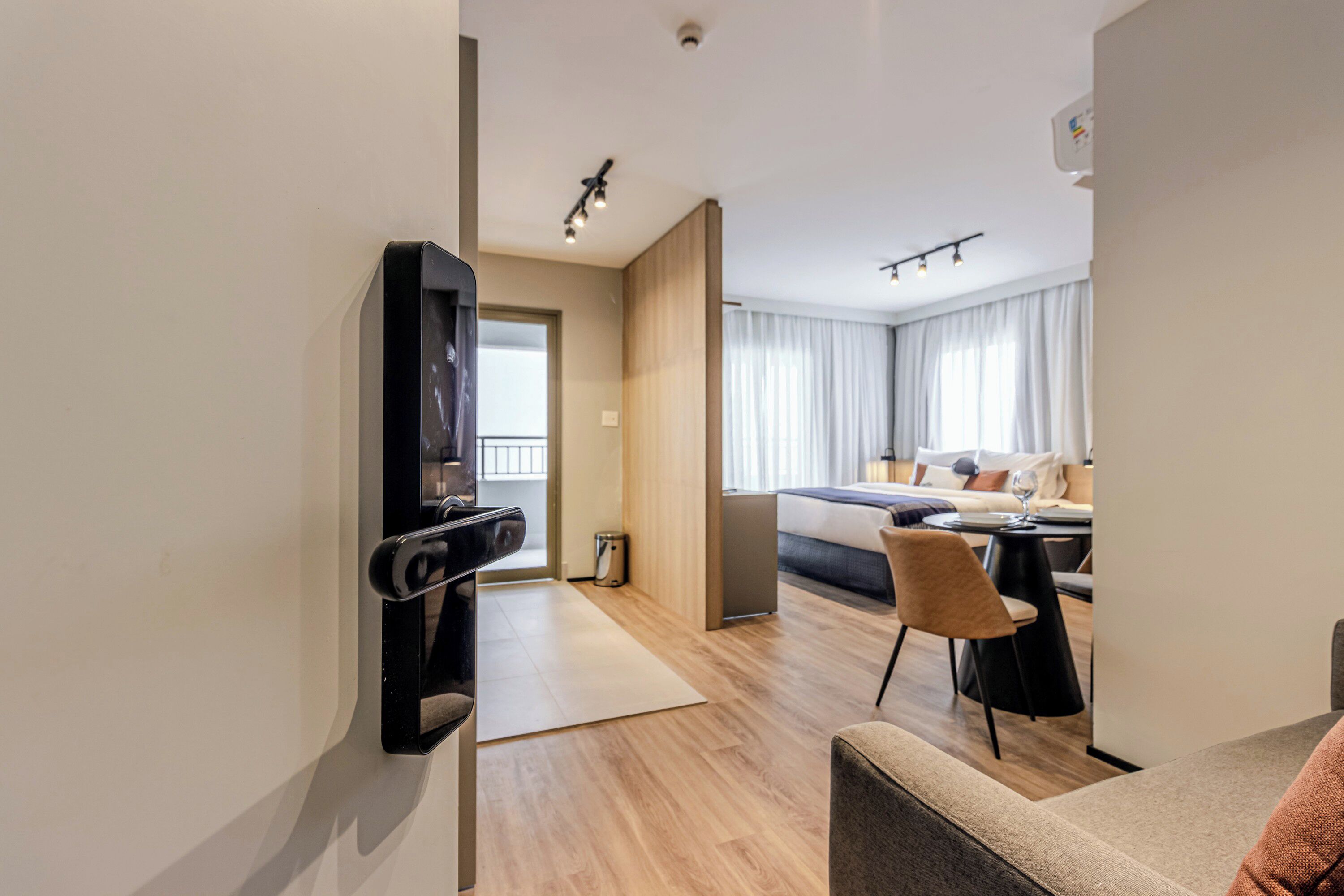 A modern hotel room with a bed, a desk, a chair, and a TV mounted on the wall.