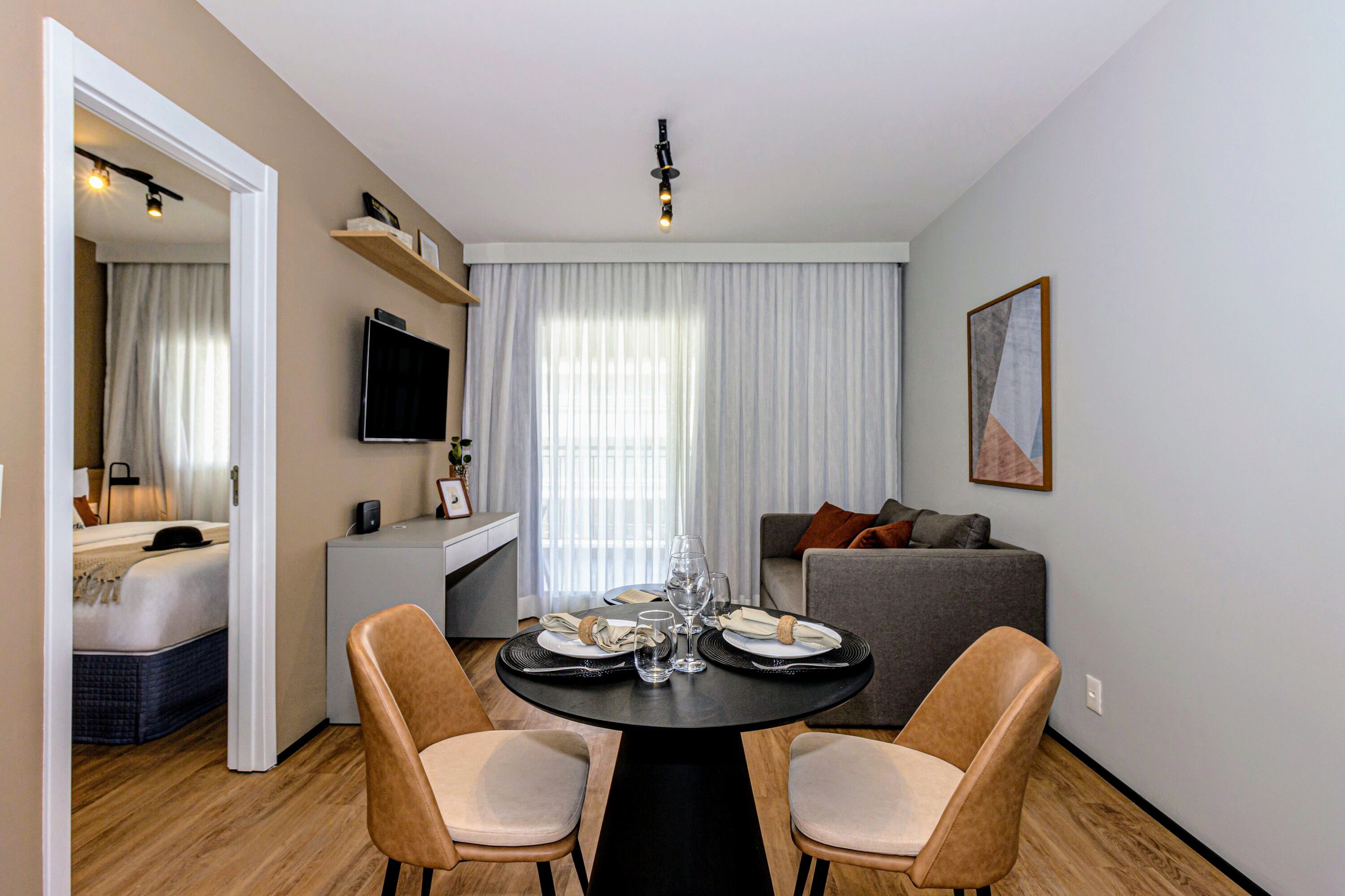 Un comedor moderno con una mesa redonda, dos sillas y un televisor sobre un mueble.
