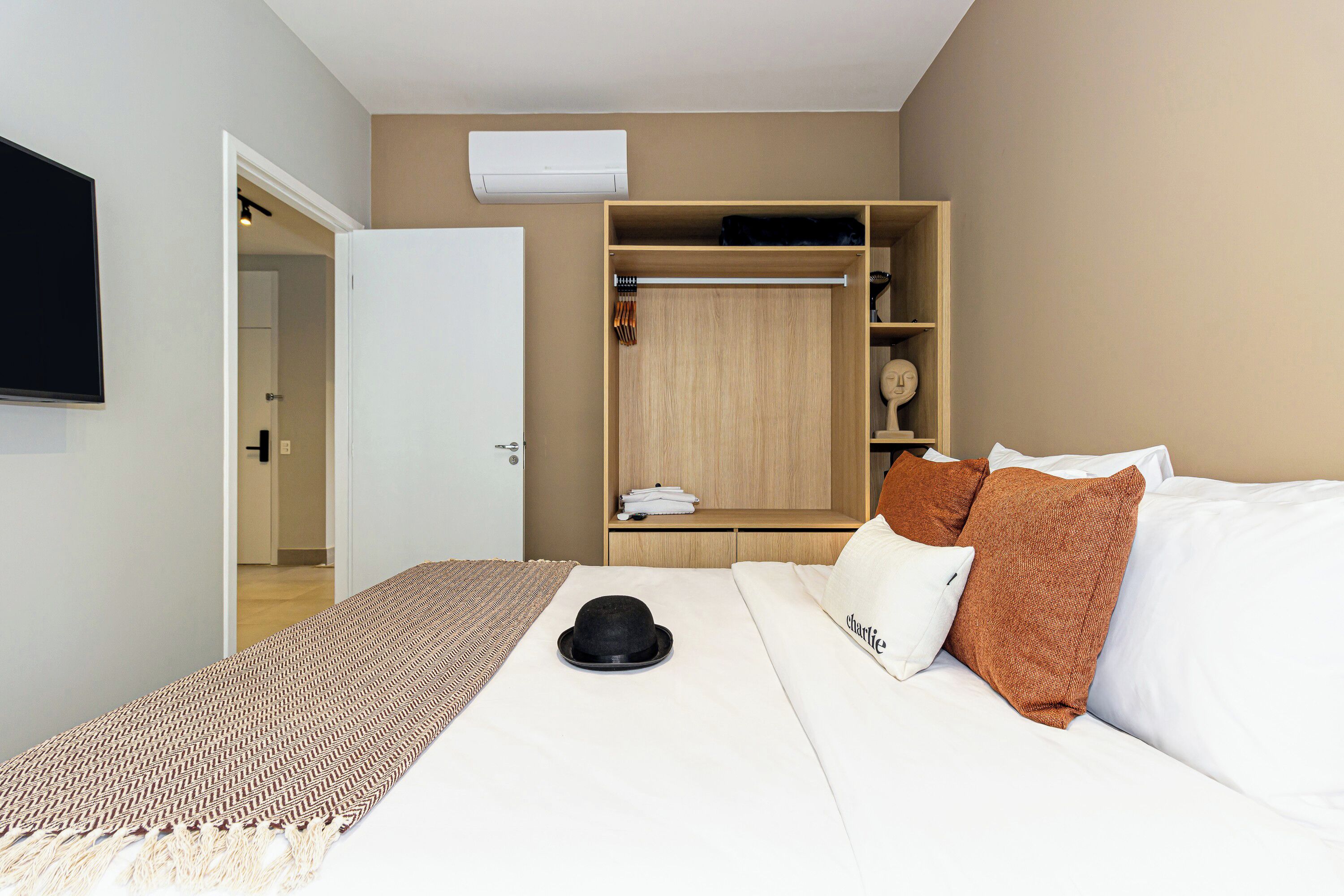 A bedroom with a bed, a wardrobe, a television, and a door leading to another room.