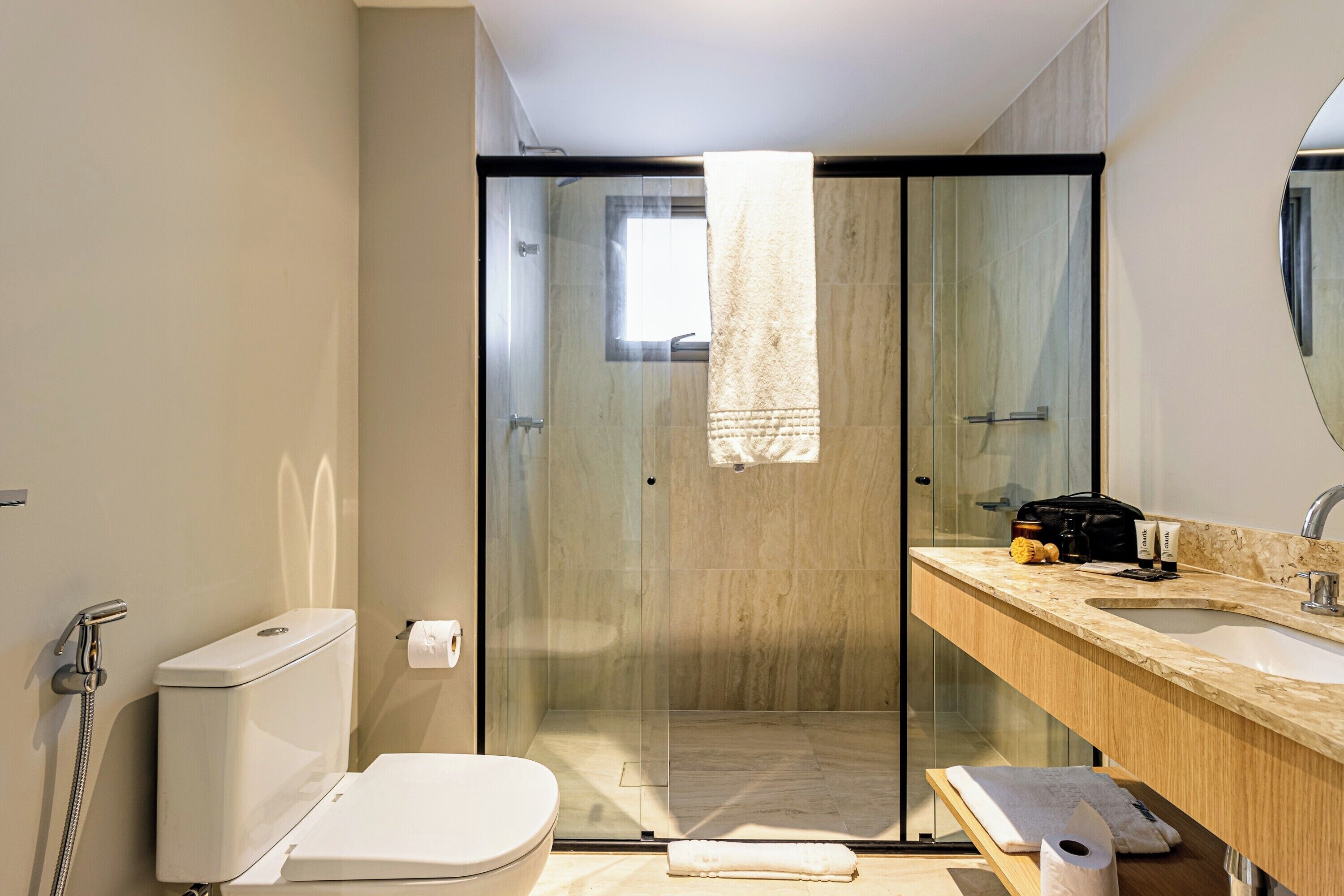 Un baño moderno con cabina de ducha de vidrio, inodoro, lavabo y espejo.