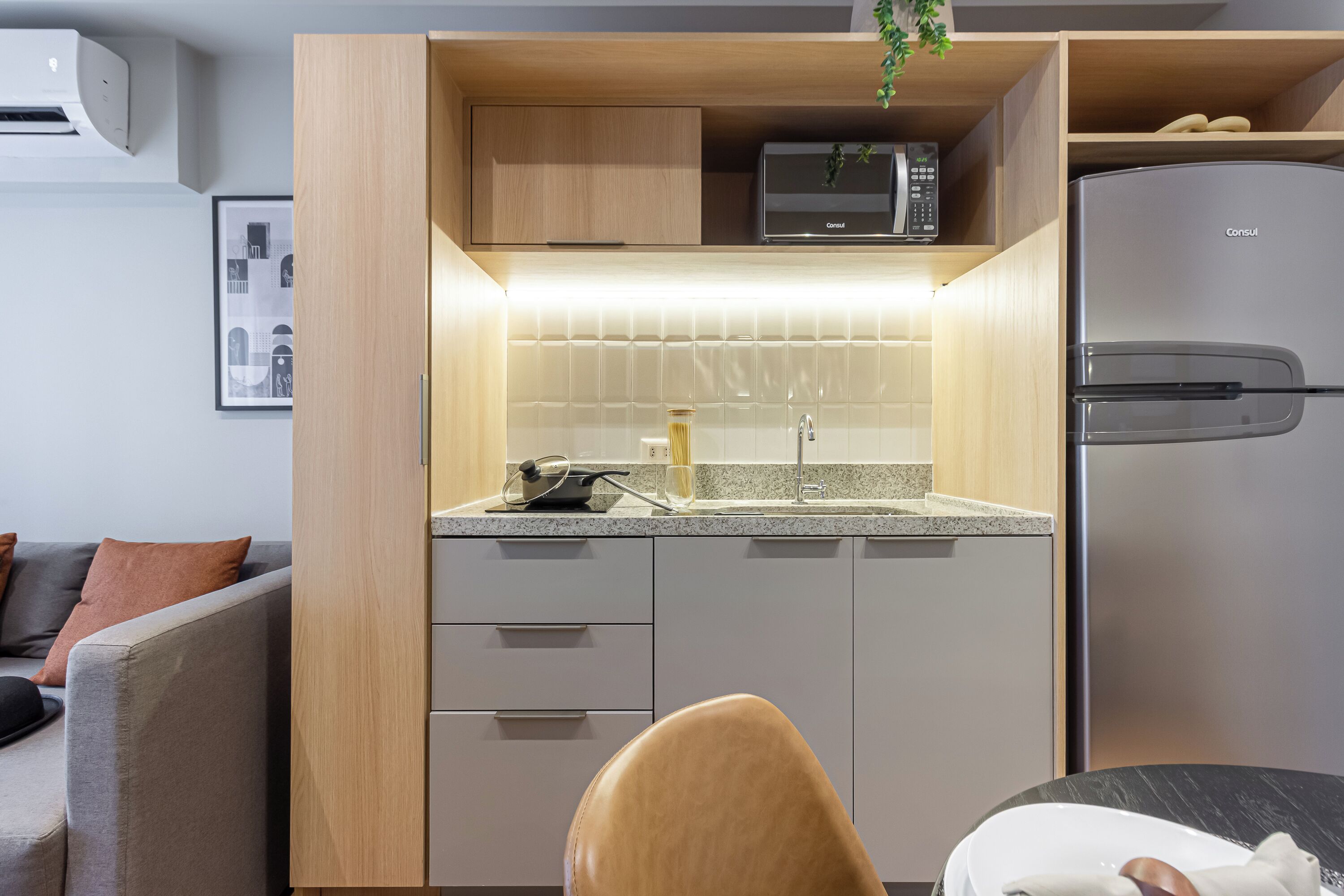 A compact kitchen with a microwave, refrigerator, and a dining area with a table and chair.