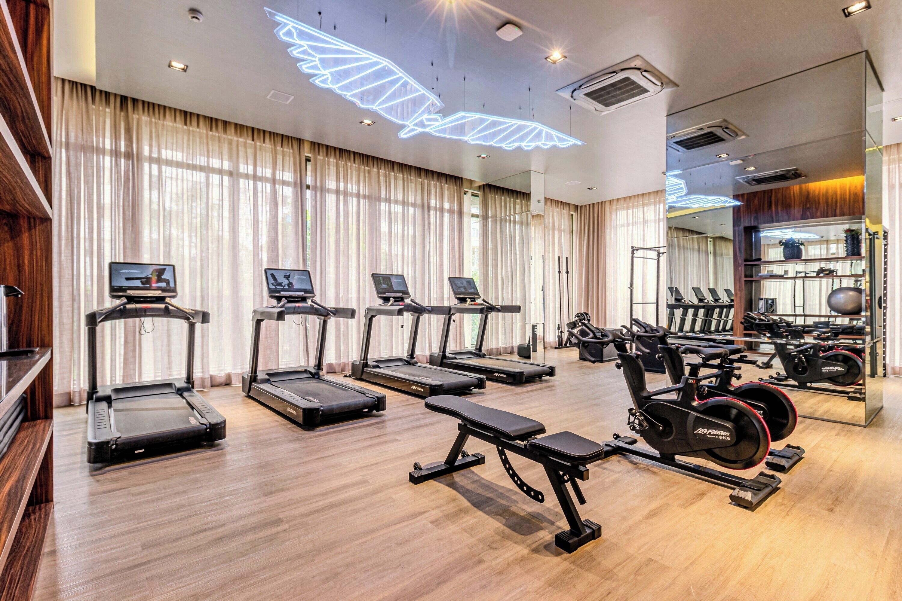 A modern gym with treadmills, a bench, and weight machines.