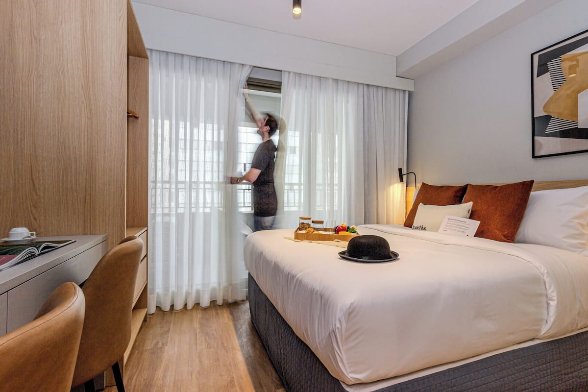 A hotel room with a bed, a desk, and a chair.