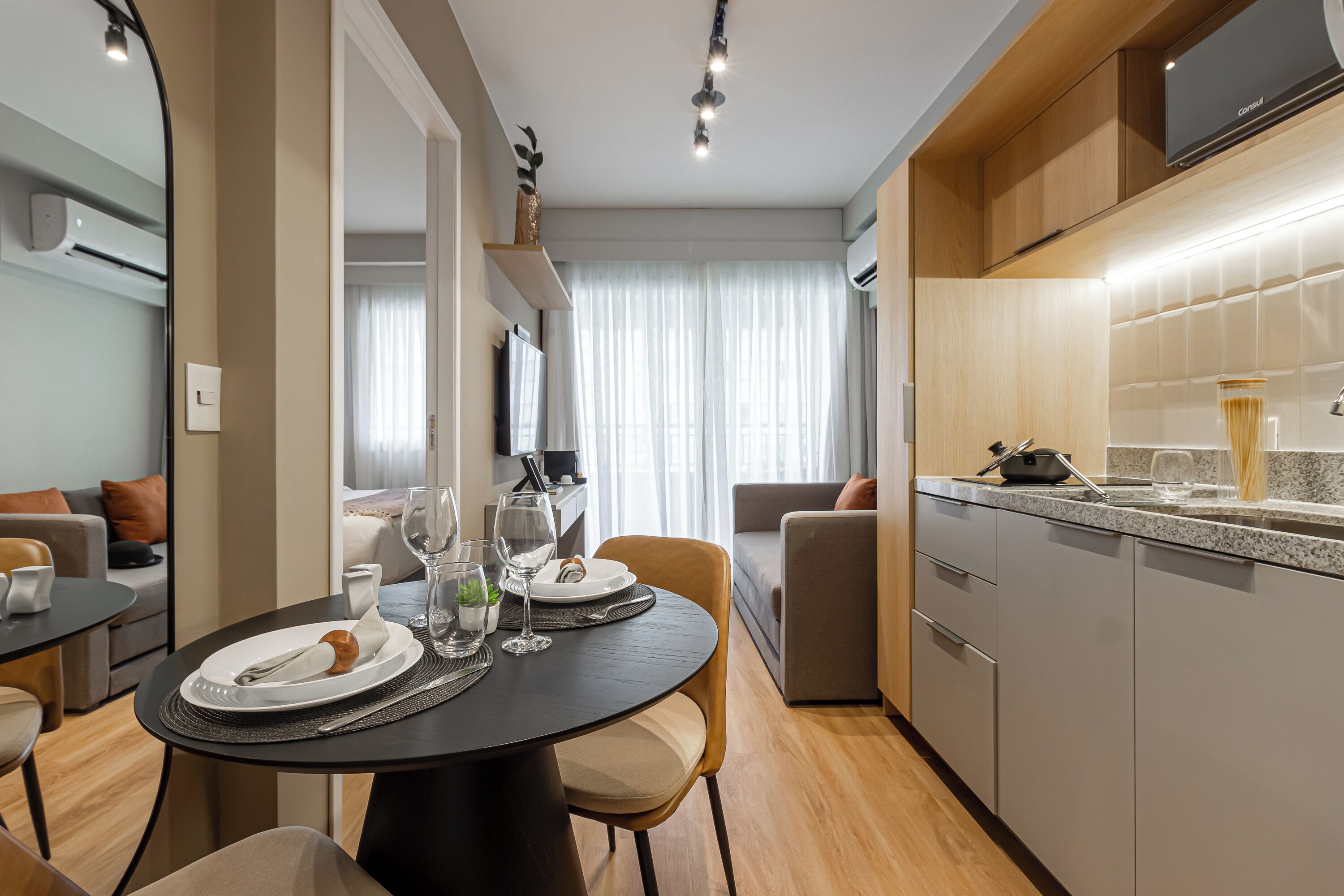 A modern kitchen with a built-in oven, a dining area with a round table, and a living area with a sofa.