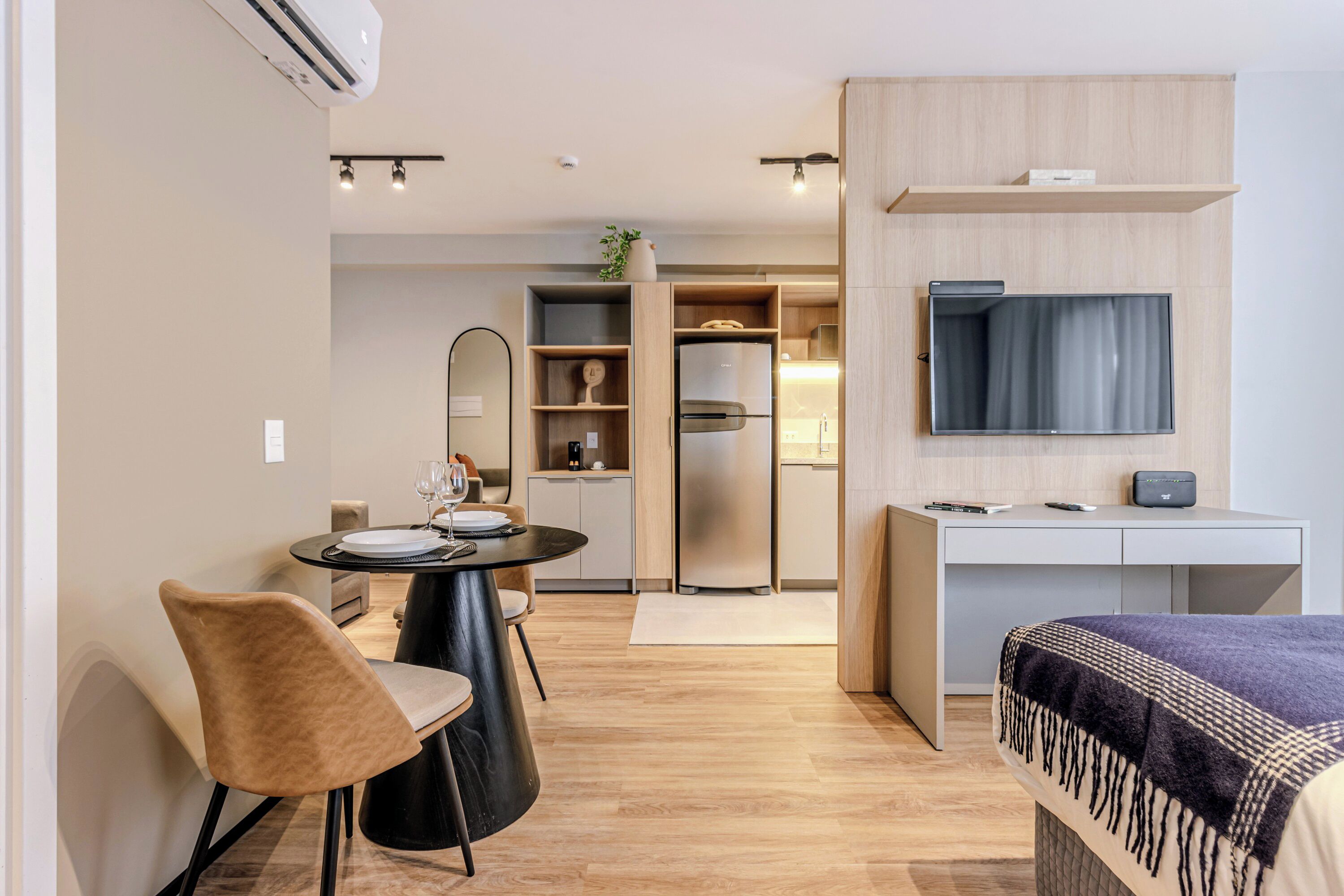 A modern hotel room with a dining area, a TV, and a wardrobe.