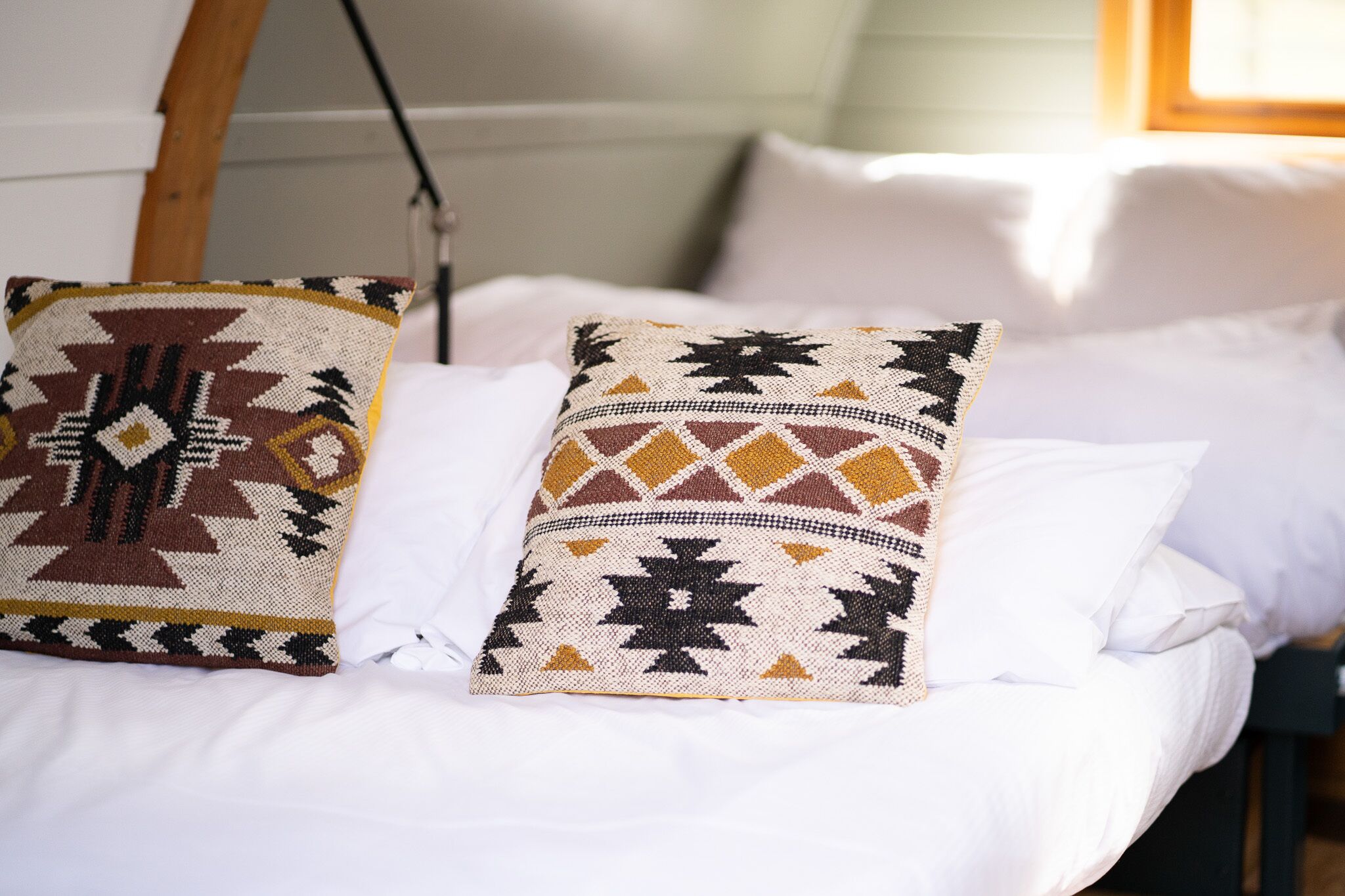 Un lit avec deux coussins décoratifs et une couverture blanche.