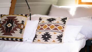 A bed with two decorative pillows and a white blanket.