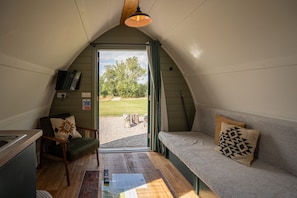 A cozy interior with a sofa, a chair, a television, and a view of the outdoors. - Luxury Cosy Cabin with Hot Tub in Rural Yorkshire (Northallerton)