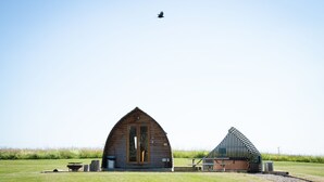 Une cabane rustique avec une grande porte en bois et une table de pique-nique devant.