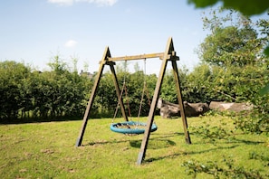 A wooden swing set with a tire swing in a grassy area with trees in the background. - Luxury Cosy Cabin with Hot Tub in Rural Yorkshire (Northallerton)