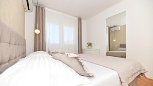 Une chambre à coucher avec un grand lit, une table de chevet ornée d’un vase de fleurs et un miroir accroché au mur.