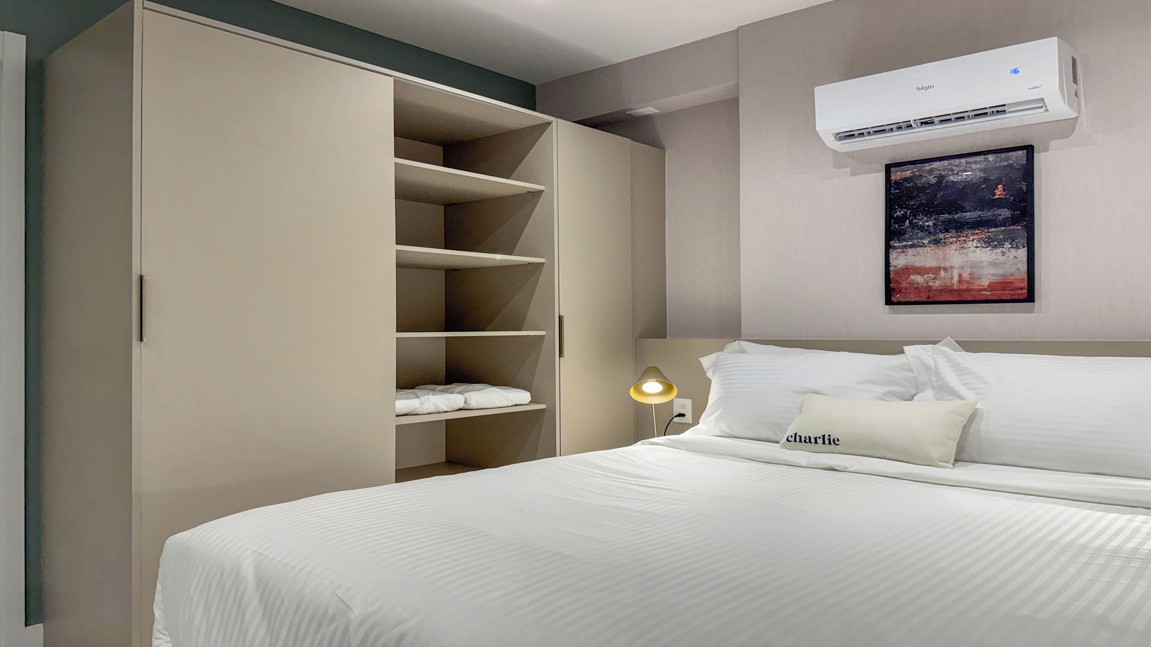 Un dormitorio ordenado con cama, armario y aire acondicionado de pared.