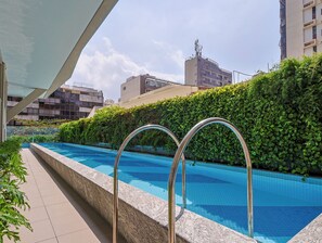 Una piscina al aire libre, sillones reclinables de piscina