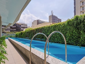 Una piscina al aire libre, sillones reclinables de piscina