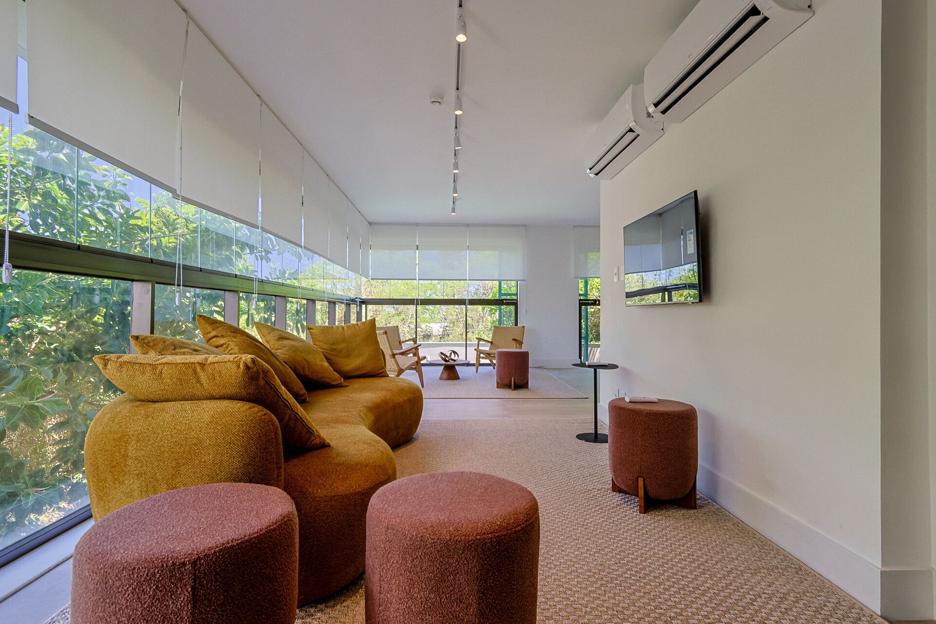 A modern living room with a sofa, ottomans, and a TV mounted on the wall.