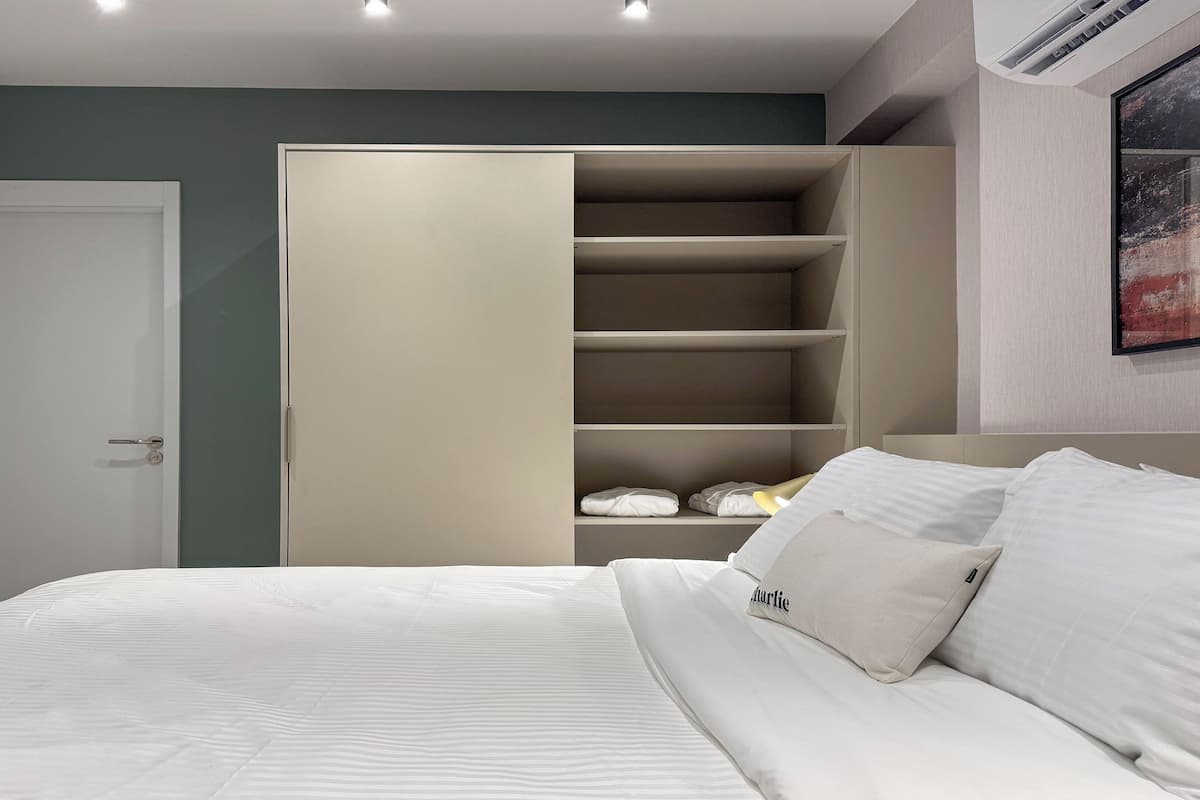 A bedroom with a bed, a wardrobe, and a painting on the wall.
