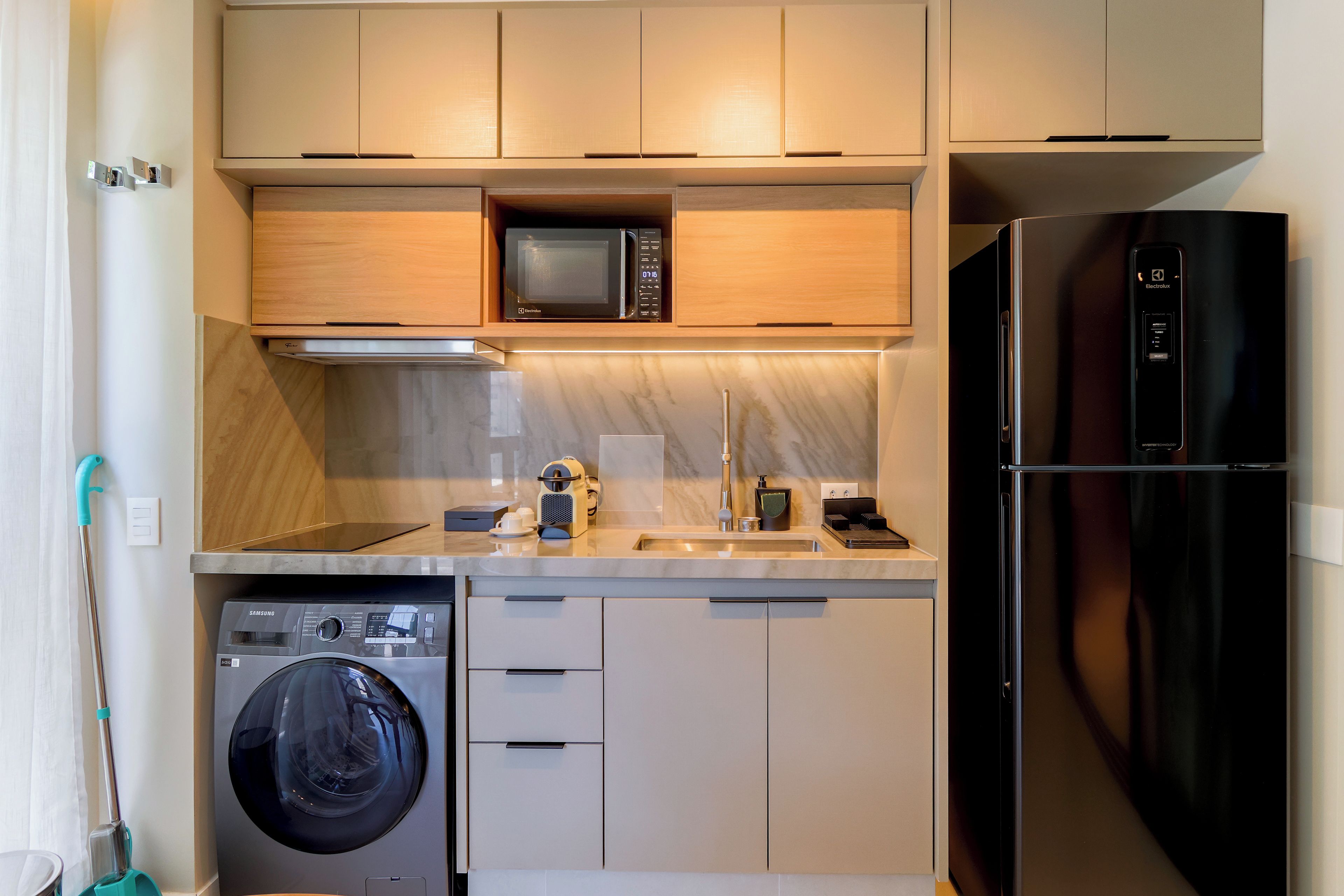 A compact kitchen with a microwave, refrigerator, and washing machine.