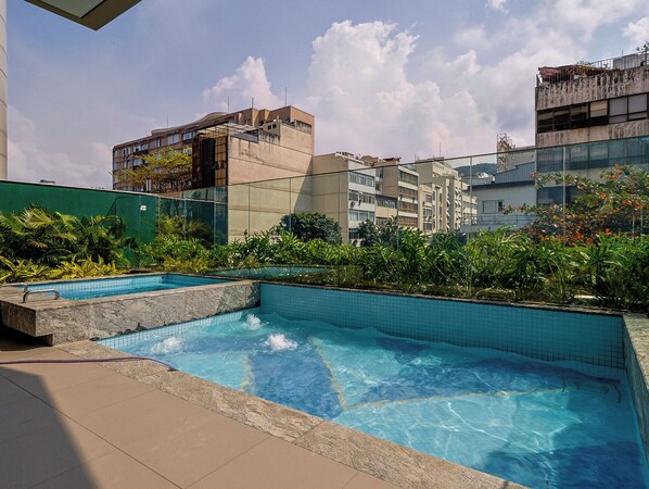 Una piscina al aire libre, sillones reclinables de piscina