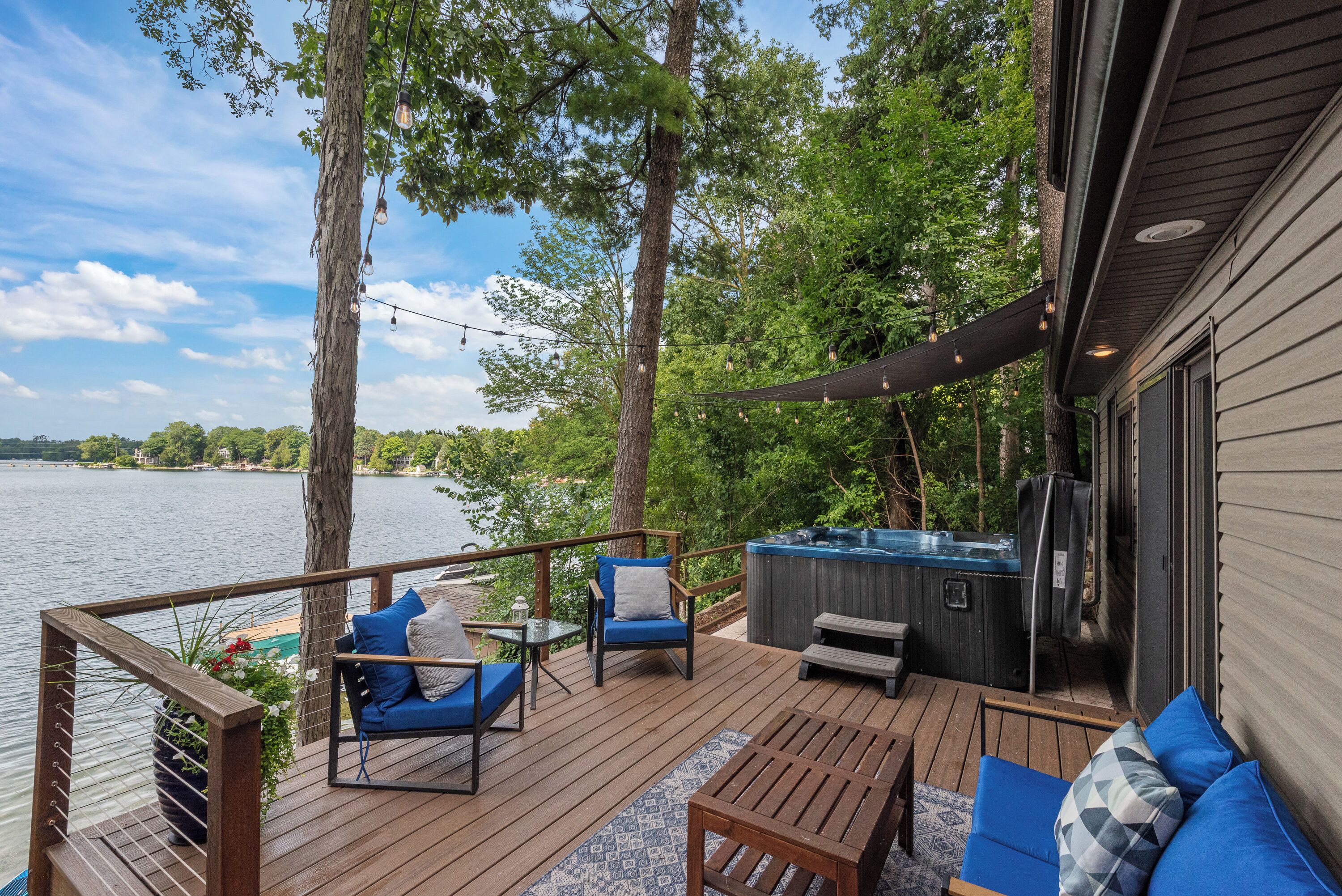 Una terraza con mobiliario exterior, un jacuzzi y vista a un lago.