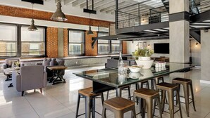 Une cuisine moderne dotée d’un îlot central en verre, de tabourets de bar et d’un coin salon avec des canapés et une table basse.
