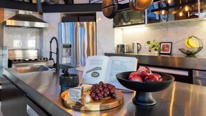 Une cuisine moderne avec des appareils en acier inoxydable, un livre posé sur le comptoir et un bol de raisins.