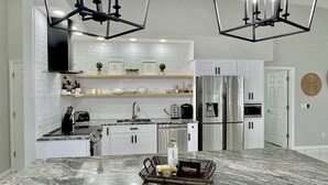 Una cocina moderna con una isla de mármol, electrodomésticos de acero inoxidable e iluminación colgante.