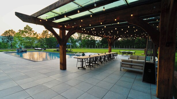 Une terrasse extérieure avec une piscine, une pergola en bois et un espace salon extérieur.
