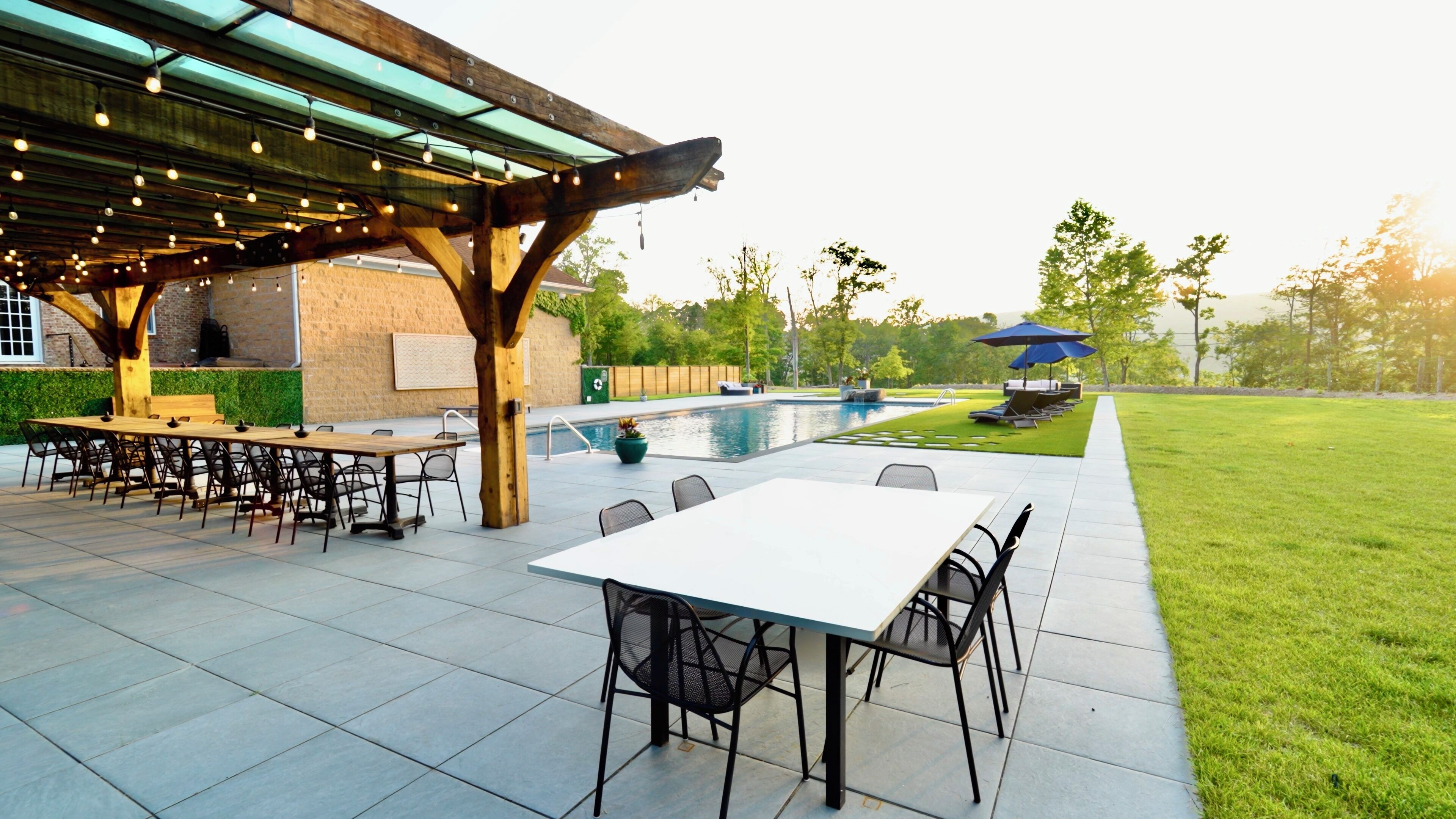 An outdoor patio with a pool, covered seating area, and a dining setup.