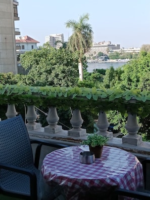 A balcony with a checkered tablecloth, a potted plant, and a metal bowl. - The H Zamalek Suites (Cairo)