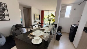 A modern kitchen with a central island, dining table set with plates, cups, and cutlery. - Mountain View, Pool & Gym (2506) (Sabaneta)