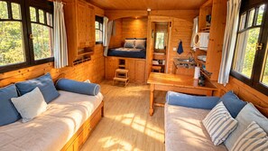 A cozy cabin interior with a sofa, a bed, a small table, and a kitchenette.